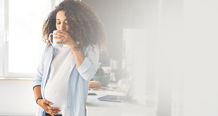 Woman drinking from cup 27 weeks pregnant
